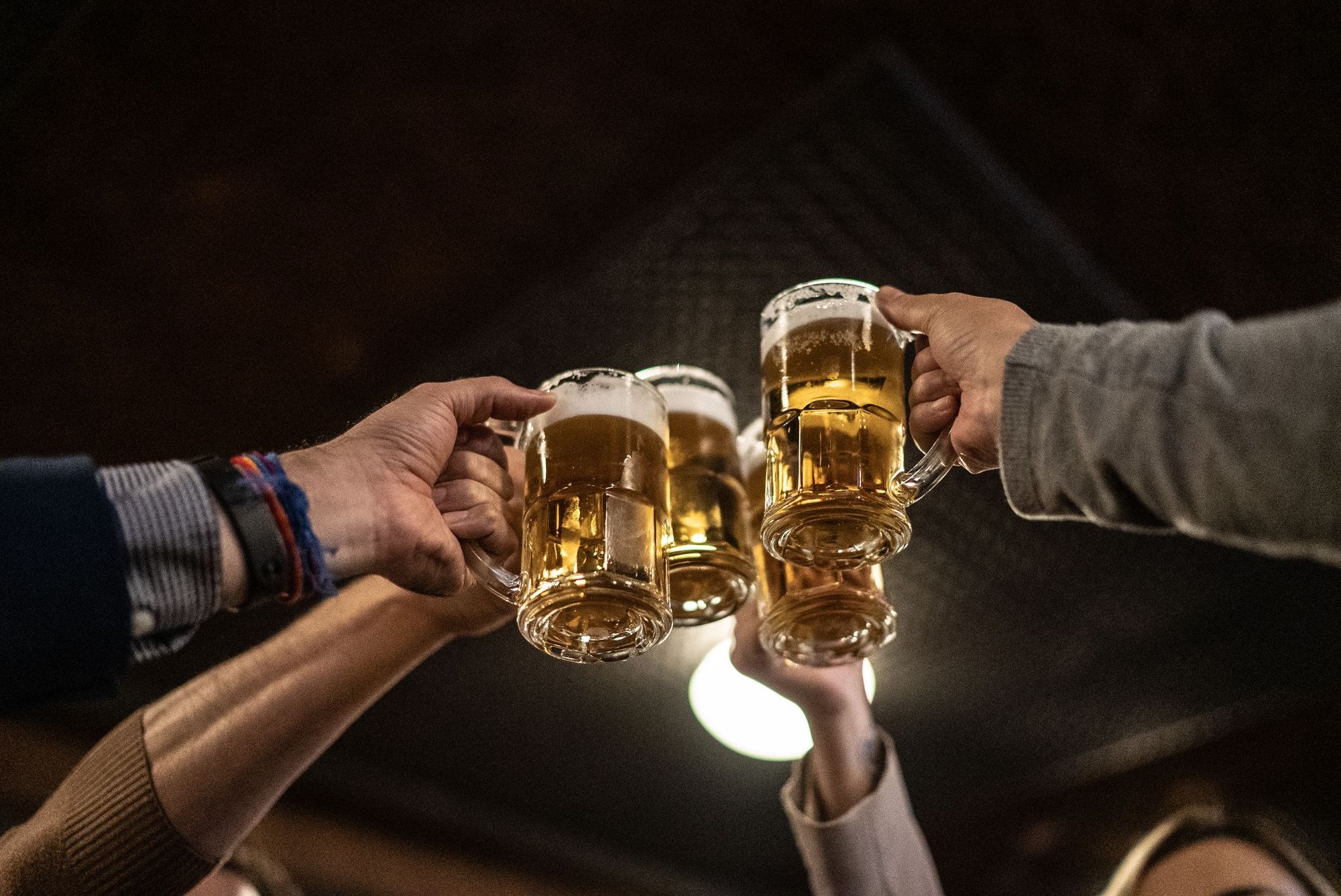 Pessoas segurando canecas de chopp.